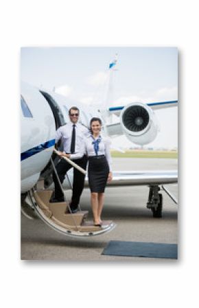 Confident Airhostess And Pilot Standing On Private Jet's Ladder