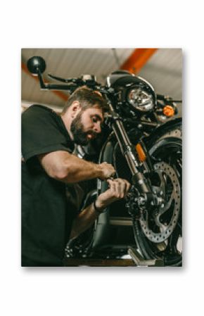 A professional mechanic unscrews the front wheel of a motorcycle. Bike is on the lift at the service station.