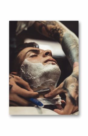 Crop stylish applying foam on customer's cheeks for shaving while working in barbershop.
