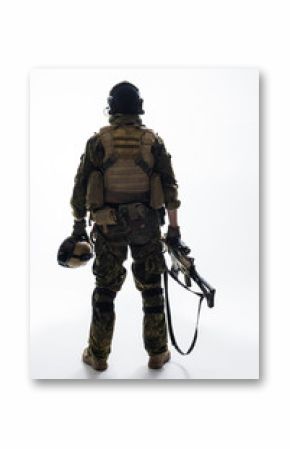 Full length soldier keeping modern weapon while turning back to camera. Army concept