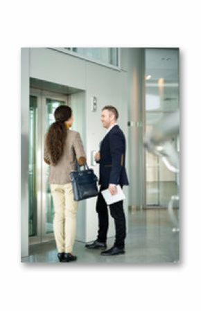 Full length portrait of two business people, man and woman, chatting cheerfully while waiting for elevator in office building