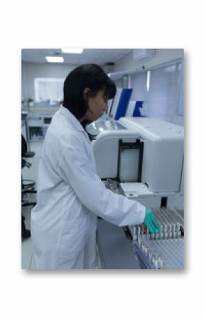 Laboratory scientist in white coat and gloves is loading sample tubes into analyzer at bench