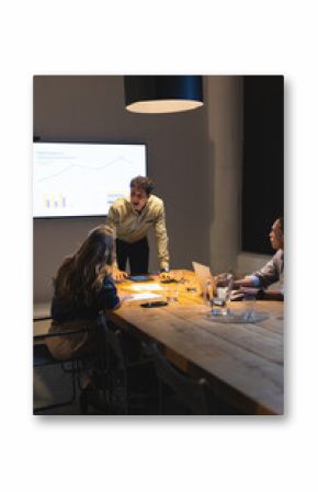 Businessman presenting data on screen during late-night meeting in modern office