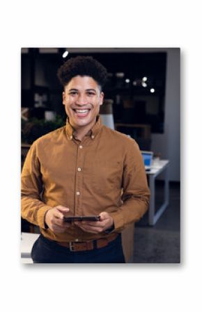 Smiling businessman holding tablet in modern office during evening work session