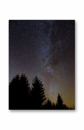 Milky way from forest in the Brecon Beacons National Park. Relatively clear view of the galaxy with coniferous forest silhouette in foreground, in Wales, UK