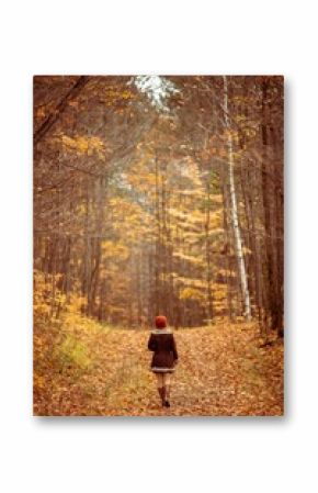 Vertical back view of a woman in cowboy boots walking along a path in colorful autumn forest