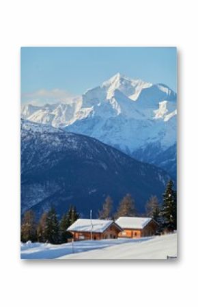 Vertical shot of the small huts nestled between the snowy mountains