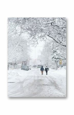 Back view of two young kids with backpacks walking along a snowy street with white trees in Ottawa