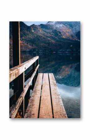 Vertical shot of a wooden bench in front of a still pond in a mountainous park