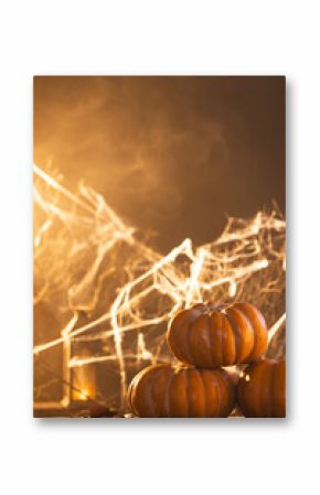 Vertical image of pumpkins and spiderweb decorations with copy space on orange background