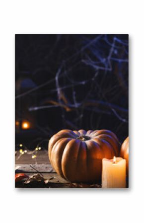 Vertical image of pumpkins, candle and spiderweb decorations with copy space on black background