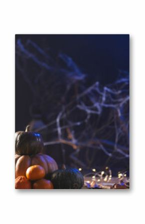 Vertical image of pumpkins and dry leaves with copy space on dark background