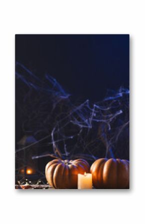 Vertical image of pumpkins, candle and spiderweb decorations with copy space on black background