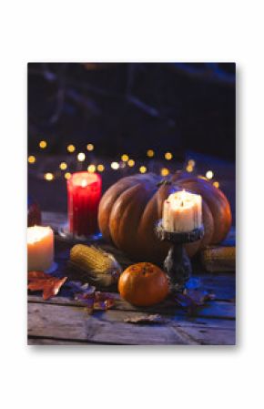 Vertical image of pumpkins, oranges, corn cobs and candles with copy space on dark background