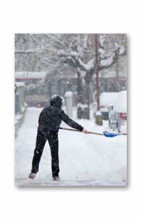 Woman shoveling snow from a sidewalk after a heavy snowfall in a