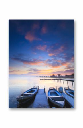 Peaceful sunrise with dramatic sky and boats and a jetty