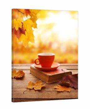 Autumn background. Autumn leaves, book and cup of tea on wooden table in park.