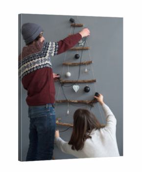 Young couple decorating a wooden handmade Christmas tree