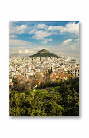 Apartment buildings located near green mountain peak on cloudy day in Athens, Greece