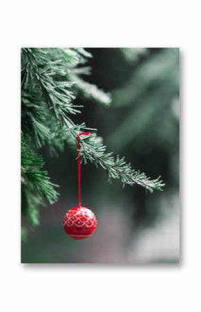 Red wooden ball hainging from Christmas tree in garden in winter