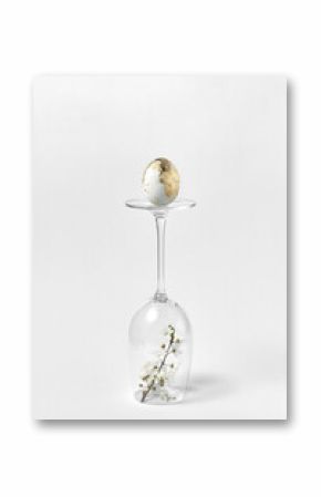 Easter golden egg on a glass with flowers.