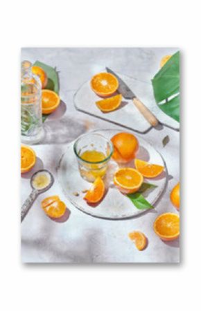 Top view of whole and half of ripe oranges arranged on table with knife and glass with juice
