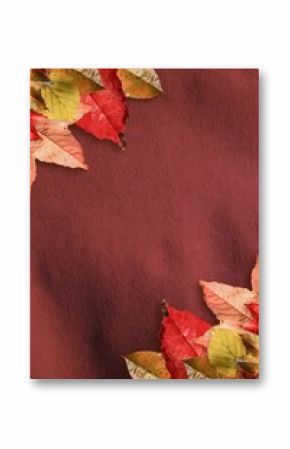 Decorative clusters of autumn leaves are framing flat design burgundy-red background, copy space