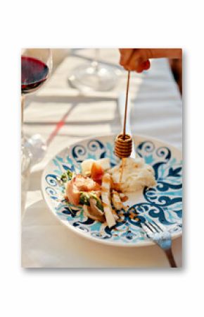 Hand holding honey dipper above plate