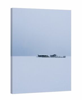 Vertical shot of buildings in the middle of a plain snow field under a very cloudy sky