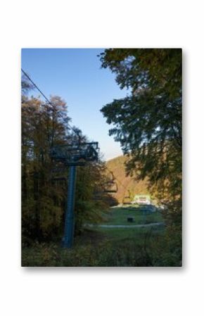 Vertical shot of a ropeway and colorful trees under the clear sky in autumn