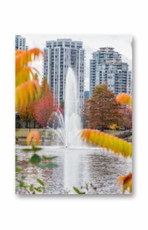 Fountain with autumn trees and modern buildings in the background