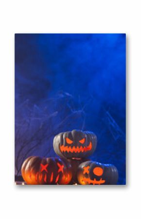 Vertical image of three carved pumpkins and candles with copy space on blue background