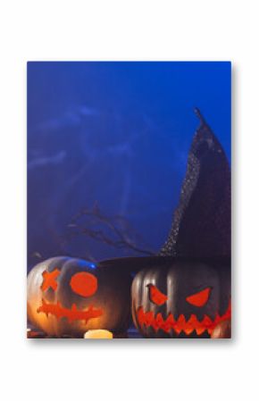 Vertical image of carved pumpkins and candle with copy space on blue background