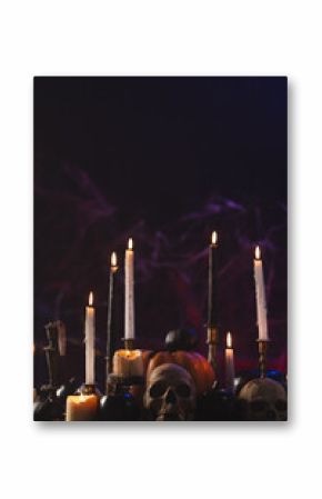 Vertical image of pumpkins, skulls and candles with copy space on purple background