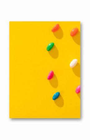 Directly above view of multi colored candies arranged by copy space on yellow background