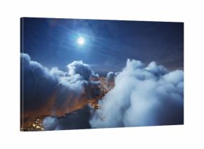 Flying over the deep night timelapse clouds with moon light. Seamlessly looped animation. Flight through moving cloudscape over night city lights. Perfect for cinema, background, digital composition.