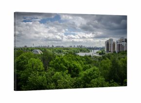 KHIMKI, RUSSIA - JUNE 1, 2017: The view from the Ferris wheel at green park. Under construction skyscrapers on the horizon. The sense of height above the trees.