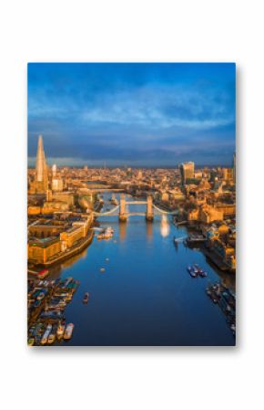 London, England - Aerial skyline view of London including iconic Tower Bridge with red double-decker bus, Tower of London, skyscrapers of Bank District at golden hour early in the morning