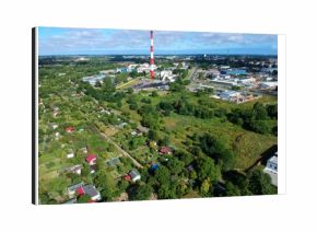 Heating plant with high chimney in city, close to the allotment gardens, aerial view