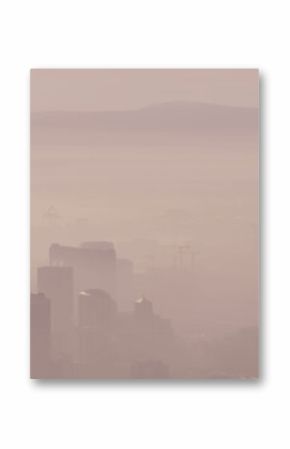 General view of foggy cityscape with modern buildings over landscape of mountains