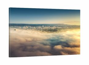 Flying above the clouds, view toward the city