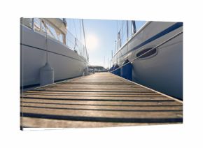 Marina with anchored boats.  Perspective of small floating pier on still water.