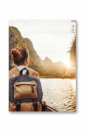 woman with backpack traveling by boat enjoying sunset among of mountains.
