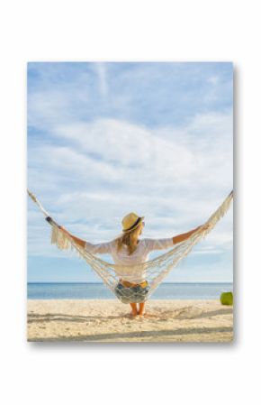Woman in hat sitting in hammock on the beach. Travel and vacation concept.