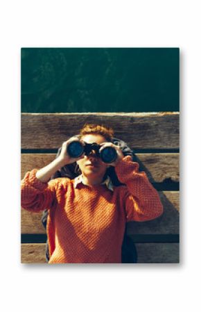 Young Girl Lies On A Pier Near The Sea And Looks Through Binoculars. Travel Search Journey Concept