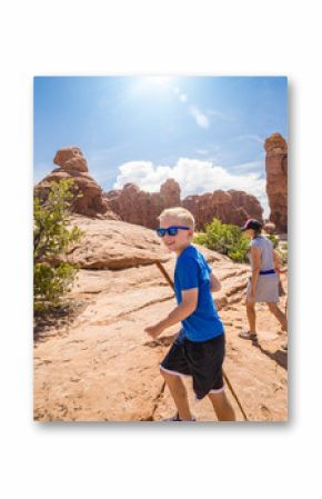 Happy family hiking together in the beautiful rock formations of Arches National Park. Walking along a scenic trail with large rock unique formations in the background