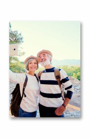 Tourism and technology. Traveling senior couple taking selfie together against ancient sightseeing background.