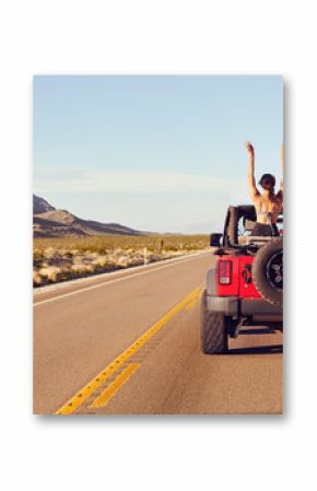 Rear View Of Friends On Road Trip Driving In Convertible Car