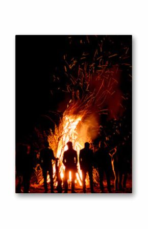 People stand near a big fire at night