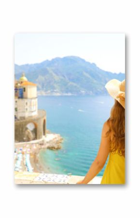 Summer holiday in Italy. Back view of young woman with straw hat and yellow dress with Atrani village on the background, Amalfi Coast, Italy